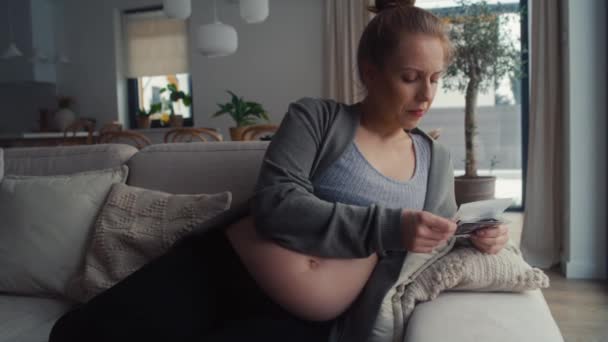 Złamana kobieta w ciąży leżąca na sofie i przeglądająca obraz ultradźwiękowy - Materiał filmowy, wideo