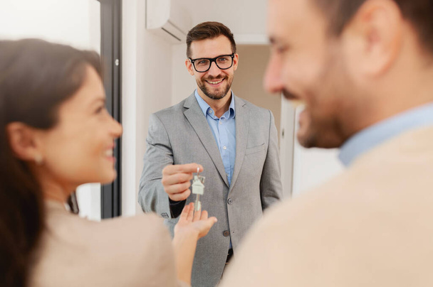 Man and his pregnant wife, talking with a real-estate agent visiting apartment for sale or for rent. Future parents buying an apartment. Real estate concept - Photo, Image