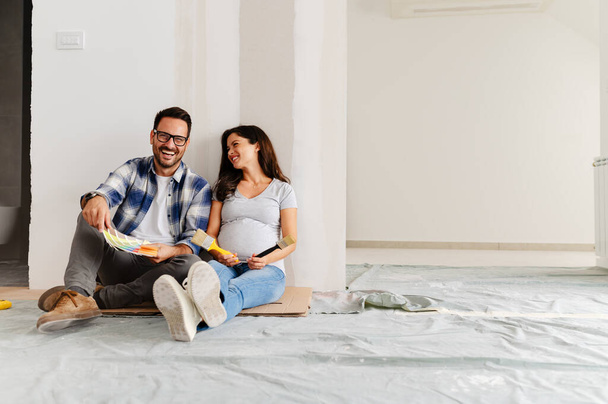 raskaana oleva nainen ja hänen miehensä valitsemalla maali väri maalaus seinät uudessa asunnossa - Valokuva, kuva