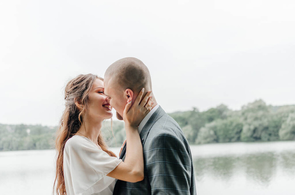 a noiva e o noivo beijam-se na margem do lago - Foto, Imagem
