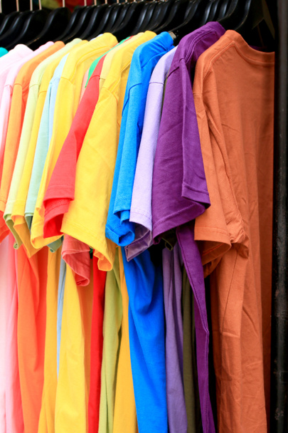 Магазин рубашки красочные ткани висит на стойке
. - Фото, изображение