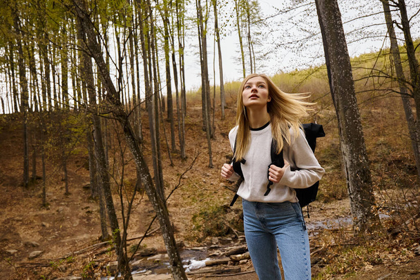 Jeune femme avec sac à dos marche dans la forêt, randonnée et camping dans un environnement naturel - Photo, image