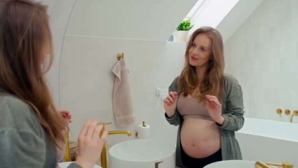 Blanke zwangere vrouw kijkt naar zichzelf in de spiegel - Video