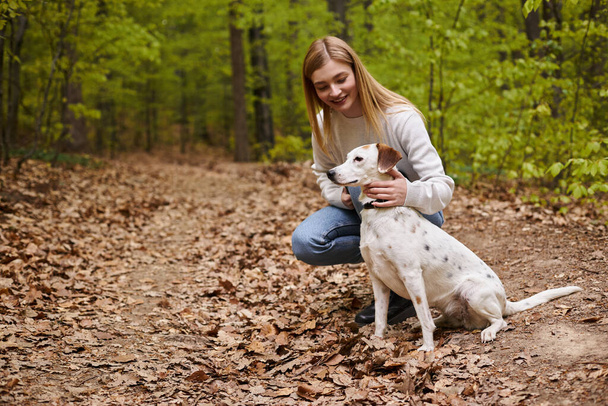Chica feliz interactuando con su mascota mirando perro senderismo descanso con vista al bosque - Foto, Imagen