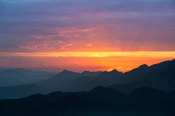 Siluety hor ve zlatém západu slunce. Pohybující se mraky na oranžové obloze. Teplá zimní horská scenérie na severním Tchaj-wanu, Shuangxi Buyanting Pavilion. - Fotografie, Obrázek