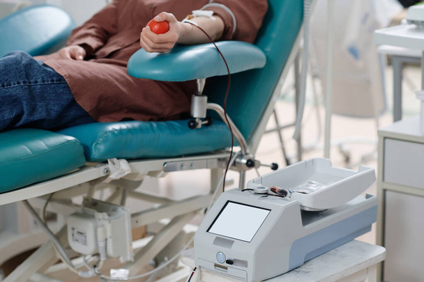 Visiteur de l'hôpital méconnaissable faisant don de sang dans un sac transparent placé sur une machine à mélanger - Photo, image