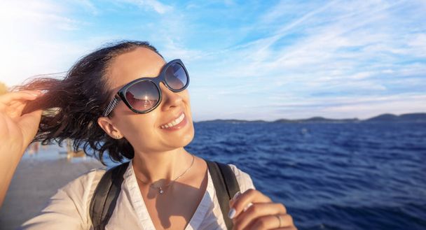 gelukkig jong vrouw toerist bij zonsondergang door de zee. - Foto, afbeelding