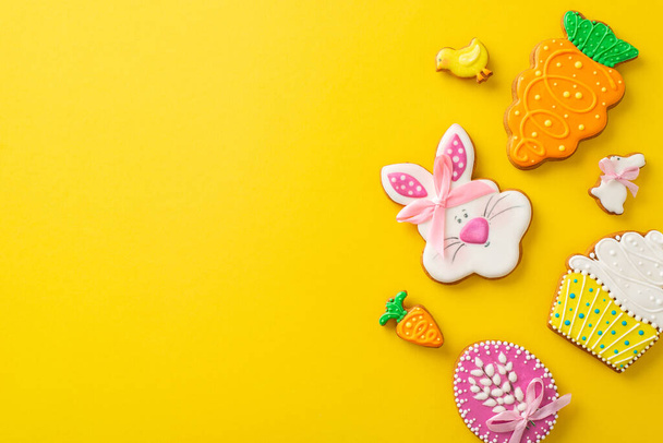 Easter-themed baking concept. Top view photo of a table set of playful themed shaped gingerbreads on a lively yellow surface. Great for advertising - Photo, Image