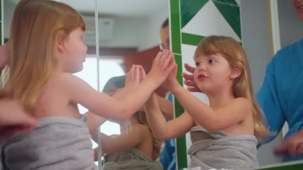 Glückliche Mutter kämmt ihren kleinen süßen Töchtern vor dem Spiegel die Haare. Zeit mit ihrem Kind. Kinderbetreuung, Mutterschaft. - Filmmaterial, Video