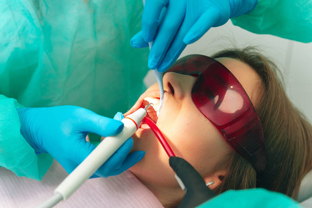 Tandarts onderzoek vrouwelijke patiënttanden met een mondspiegel en tandheelkundige graafmachine. - Foto, afbeelding