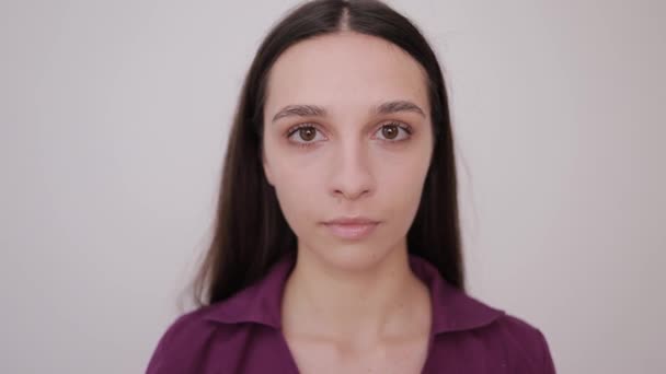 Portrait of a smiling young woman with big eyes. Brunette on a gray background. Slow motion - Footage, Video