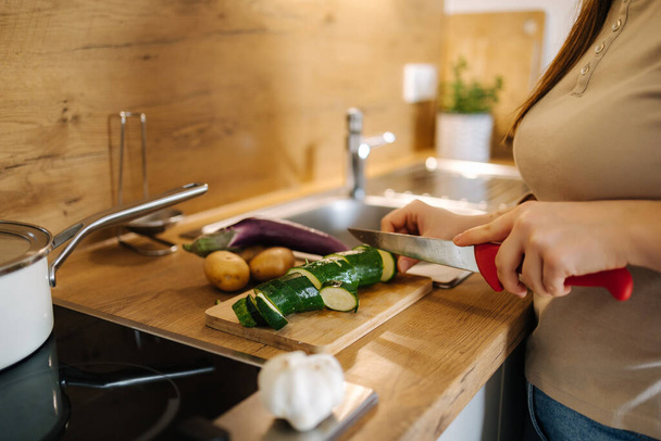 Photo of a woman cutting zucchini on a wooden board. Home food concept . High quality photo - Photo, image