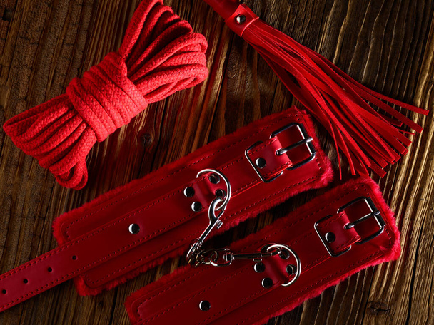 BDSM sex toys set in a red color over aged wooden planks backdrop - Photo, Image