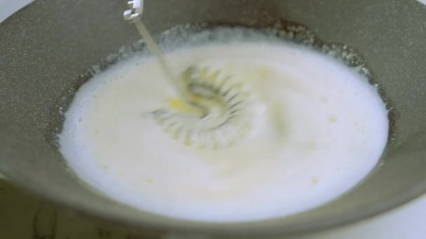 Подготовка блинного теста. Повар смешивает смесь яиц, сахара и молока в темной миске, добавляя растопленное масло. Замесить тесто металлическим смесителем. Высококачественные 4k кадры - Кадры, видео