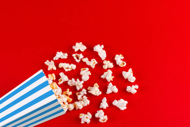 doboz popcorn csíkos különböző színekben egy piros háttér közelkép - Fotó, kép