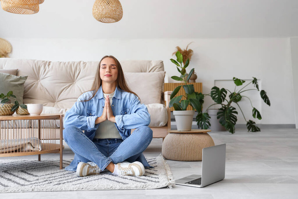 Giovane donna che medita sul tappeto in soggiorno - Foto, immagini