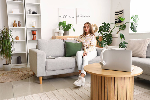 mladá žena sedící na gauči v obývacím pokoji - Fotografie, Obrázek
