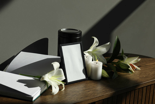 Cornice funeraria bianca, libro e fiori di giglio bianco sul tavolo di legno - Foto, immagini