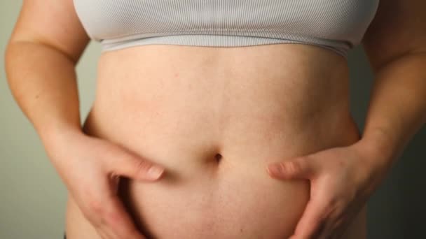 Lihava nainen yrittää sulkea farkkunsa. Naisten terveydentila. Naiset rasvaa vatsa. Lihava nainen käsi pitämällä liiallinen vatsa rasvaa. Ruokavalio elämäntapa käsite, terve vatsa lihas.  - Materiaali, video