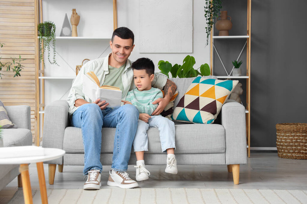 Jongeman met zijn zoontje die thuis een boek leest - Foto, afbeelding