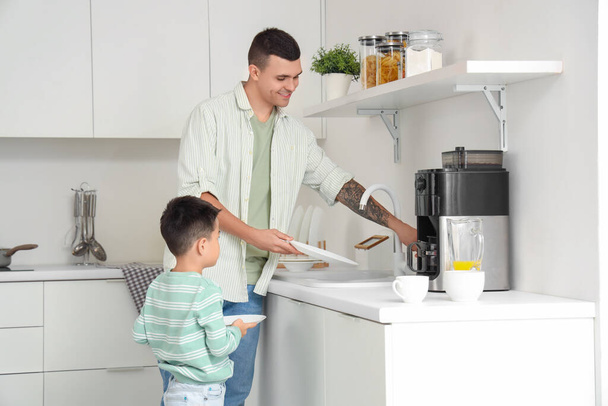 Jovem com seu filhinho lavando pratos na cozinha - Foto, Imagem