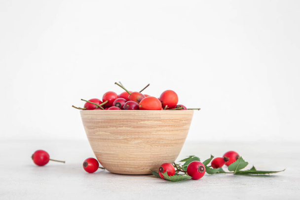 Чаша со свежими ягодами шиповника на белом фоне - Фото, изображение