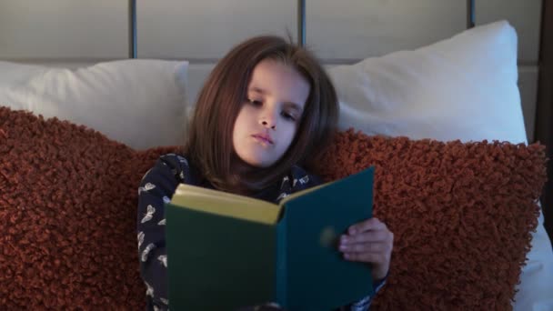 Egy kislány olvas lefekvés előtt. Álmos protestáns vallásos lány biblia könyvet olvas. Vallásos családi fogalom. Egy kislány, aki vallásirodalmat tanul. Tanulás alvás előtt. Magas - Felvétel, videó