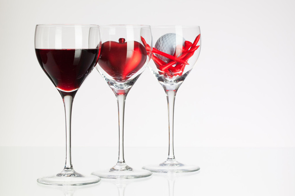 sklenice na víno s červeným vínem, srdce a golf míček  - Fotografie, Obrázek