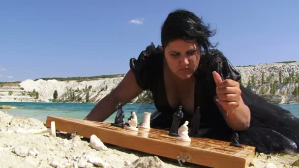 湖の近くのチェスのボードと黒のドレスの若い女性の肖像画 - 映像、動画