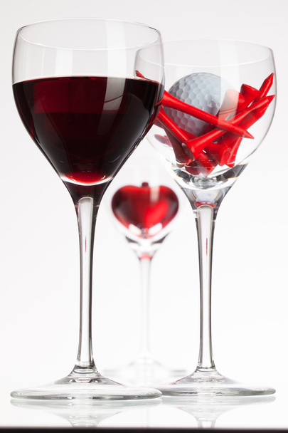 Wine glasses with red wine, heart and golf ball  - Foto, afbeelding
