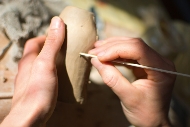 Mãos de oleiro que trabalham na decoração de vaso cerâmico
 - Foto, Imagem