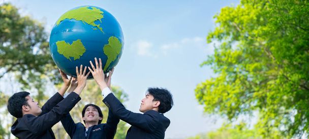 Concept de journée de la Terre avec grand globe terrestre tenu par un groupe de gens d'affaires asiatiques équipe de promotion de la sensibilisation à l'environnement avec la durabilité environnementale et le principe ESG pour un avenir plus brillant. Pneumatique - Photo, image