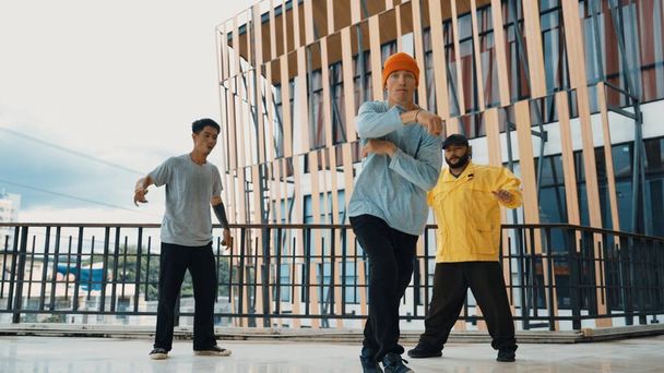 Hip-Hop-Teams tanzen Breakdance, während multikulturelle Freunde umgeben sind und Hände klatschen, um ihren Freund anzufeuern oder zum Tanzen zu ermutigen. Aktiver und energischer Streetdance. Outdoor-Sport 2024. Vorfreude. - Foto, Bild