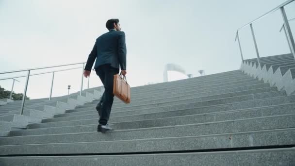 Első látásra okos üzletember sétál fel a lépcsőn táskával a kezében. Profi projektmenedzser mászni fel a lépcsőn, és megy a munkahelyre. Ügyesség növelése, előléptetés, utazás. Eredményes. - Felvétel, videó