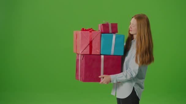 Grüner Bildschirm. Attraktive Mädchen mit einem Lächeln und einem Bündel von Geschenkboxen in den Händen. Sie verkörpert den Geist der Feier und strahlt Freude und Vorfreude auf besondere Momente aus - Filmmaterial, Video