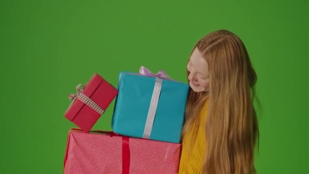 Pantalla verde. Chica atractiva con sonrisas y sostiene un montón de cajas de regalo en sus manos. Encarnando el espíritu de celebración, irradia alegría y anticipación de momentos especiales - Metraje, vídeo