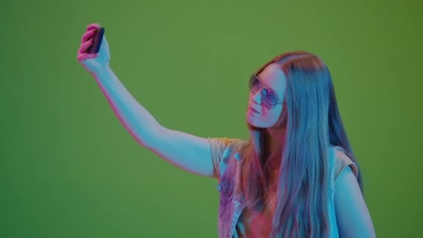 Pantalla Verde. Adolescente en luces de neón tomando un selfie, radiando positividad y altos espíritus. Una imagen moderna de los jóvenes comprometidos con la cultura digital y expresando sus vibrantes personalidades - Metraje, vídeo