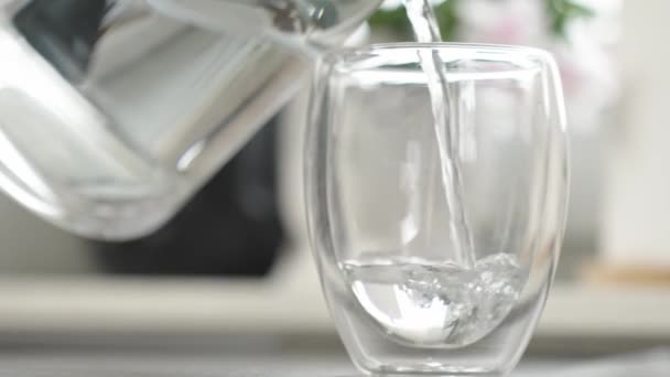 Nainen kaataa puhdasta vettä kannusta lasiin keittiössä, sammutus jano, elämäntapa terveydenhuollon käsite - Materiaali, video