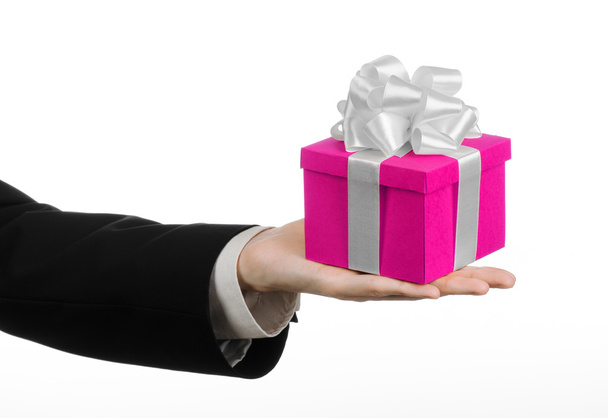 The theme of celebrations and gifts: hand holding a gift wrapped in pink box with white ribbon and bow, the most beautiful gift isolated on white background in studio - Photo, image