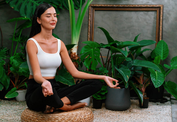 Молода жінка робить ранкову йогу і медитацію в природному саду з листям рослин, насолоджуючись самотністю і практикуючи медитативні пози. Активність і здоровий спосіб життя. Блайт - Фото, зображення