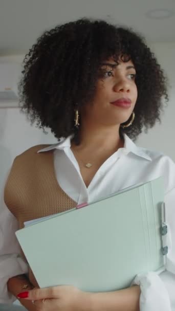 Imagen vertical de la mujer de negocios con contrato de negocios y sonriendo a la cámara en la oficina - Metraje, vídeo