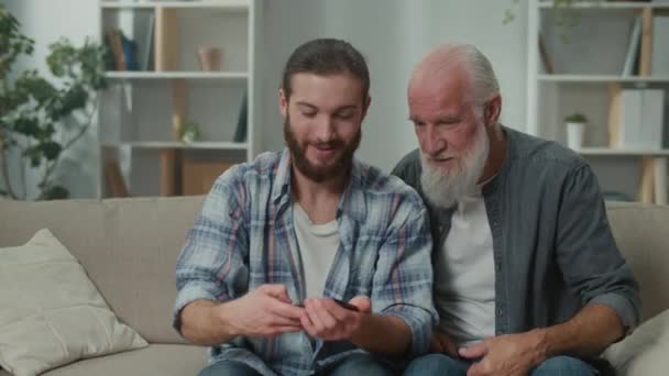 Son introducing dad to digital world, using gadgets, elder tech education, family tech bonding, intergenerational tech exchange, learning new technology together - Footage, Video