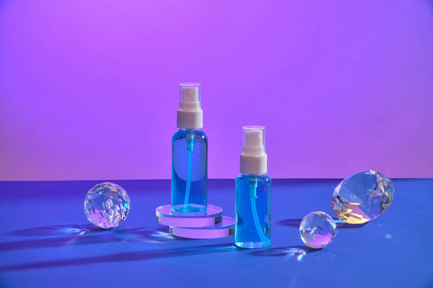 Немічені туманні пляшки, що стоять на круглих прозорих подіумах. Прикрашені алмазними і кришталевими кульками. Просування брендингу краси - Фото, зображення