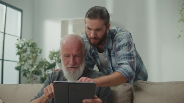 Young volunteer teaches senior how to use a tablet, bridging generation gap, tech-savvy youth, elderly learning, digital literacy, cross-age friendship, modern gadgets - Footage, Video