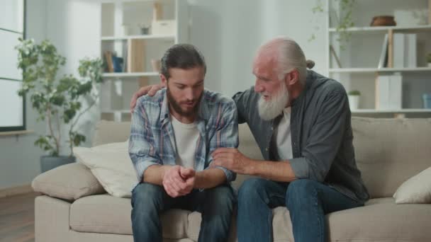 Rodinný rozhovor na gauči: mladí a starší muži mluví o životě, psychologická vzájemná podpora, mezigenerační dialog, srdečná útěcha, rady a moudrost, vřelá komunikace - Záběry, video