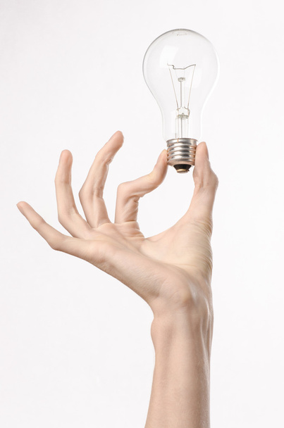 Energy consumption and energy saving topic: human hand holding a light bulb on a white background in studio - Zdjęcie, obraz