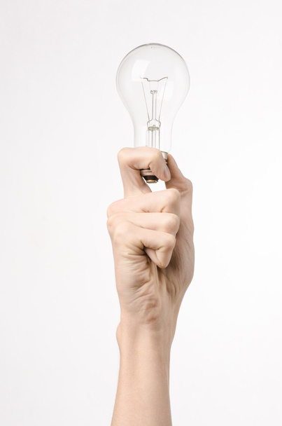 Energy consumption and energy saving topic: human hand holding a light bulb on a white background in studio - Foto, afbeelding