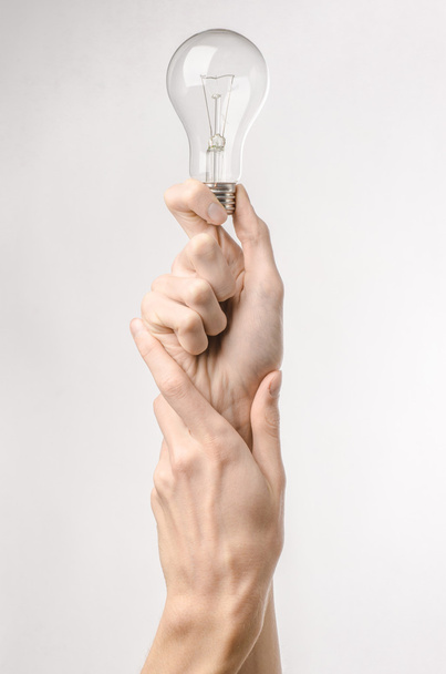 Energy consumption and energy saving topic: human hand holding a light bulb on a white background in studio - Foto, Imagen