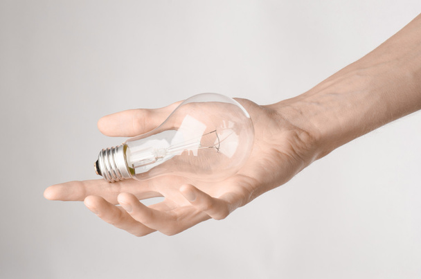 Energy consumption and energy saving topic: human hand holding a light bulb on a white background in studio - Fotografie, Obrázek