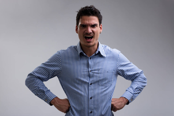 Mann in blau-weiß gestreiftem Hemd, wütend gestikulierend und große Missstände signalisierend. Wenn Ihr Verhalten anhält, wird er Ihnen eine Lektion erteilen - Foto, Bild